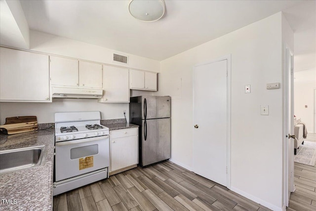 kitchen featuring stainless steel refrigerator, white gas range, white cabinetry, and light hardwood / wood-style floors