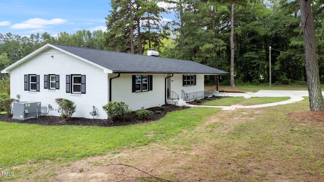 ranch-style home featuring cooling unit and a front yard