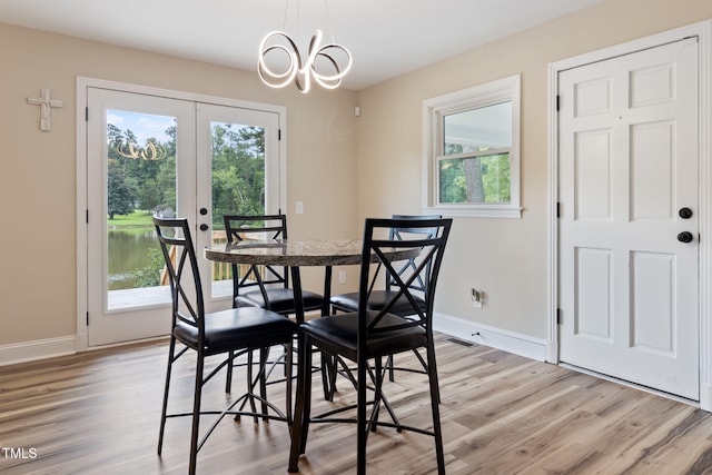 dining area with an inviting chandelier, a healthy amount of sunlight, and light hardwood / wood-style floors