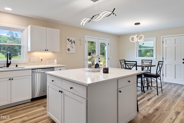 kitchen with dishwasher, sink, white cabinets, pendant lighting, and a kitchen island