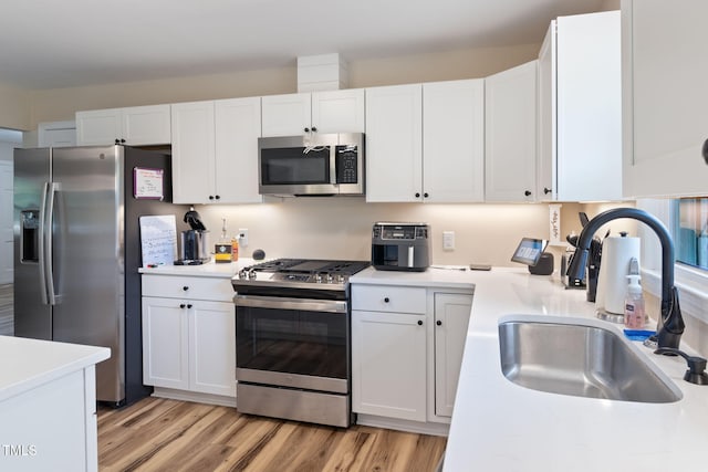 kitchen featuring white cabinets, stainless steel appliances, light hardwood / wood-style floors, and sink