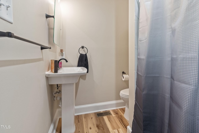 bathroom with hardwood / wood-style flooring and toilet