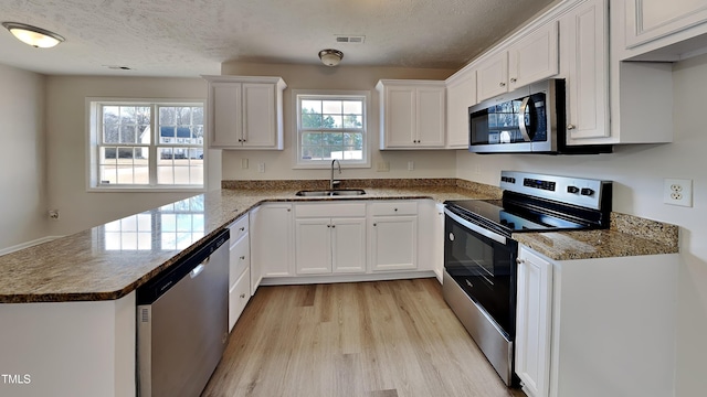 kitchen with a textured ceiling, sink, white cabinetry, and stainless steel appliances