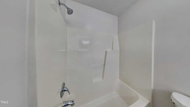 bathroom with toilet, a textured ceiling, and bathtub / shower combination