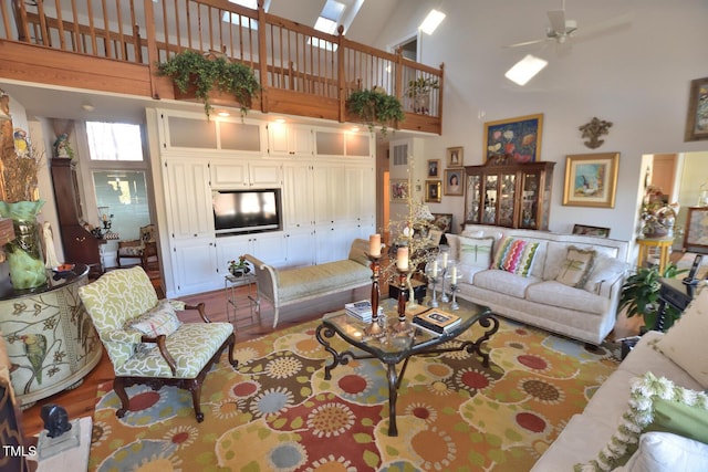 living room with a high ceiling, light wood-type flooring, and ceiling fan