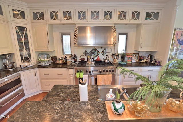 kitchen with white cabinetry, stainless steel stove, and exhaust hood