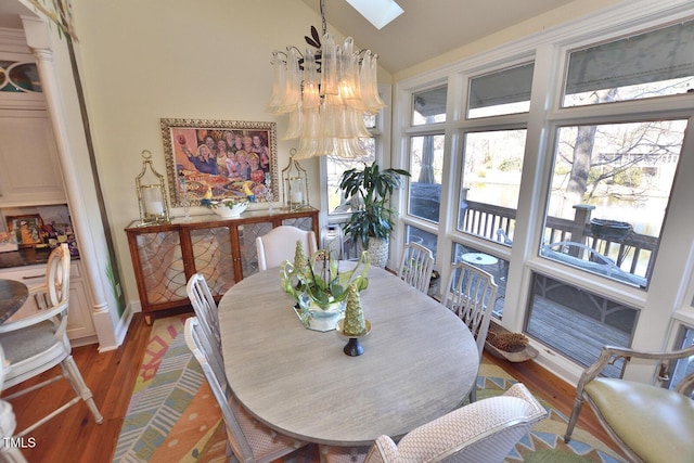 dining room featuring hardwood / wood-style floors, an inviting chandelier, and lofted ceiling with skylight