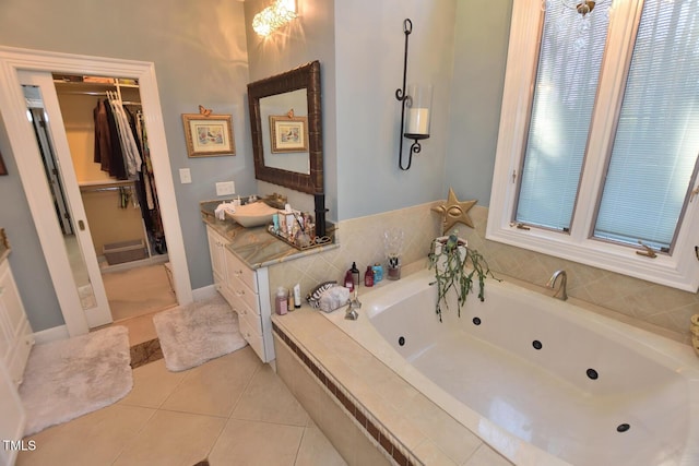 bathroom featuring tile patterned floors, vanity, and tiled bath