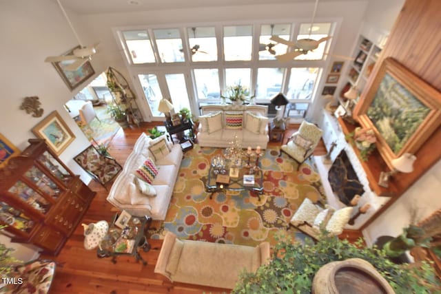 living room with wood-type flooring, ceiling fan with notable chandelier, and a healthy amount of sunlight