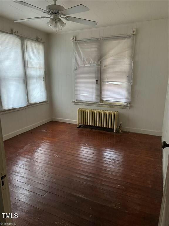 unfurnished room featuring radiator heating unit, ceiling fan, and dark wood-type flooring