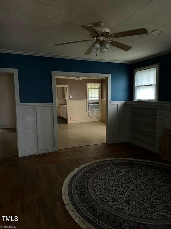 empty room with wood-type flooring, cooling unit, ceiling fan, and crown molding