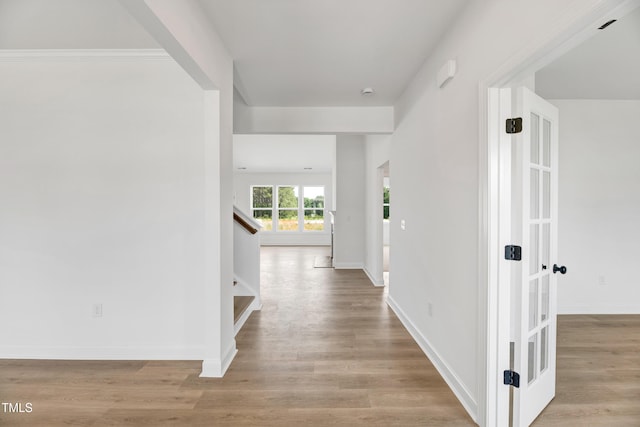corridor featuring stairs, wood finished floors, and baseboards