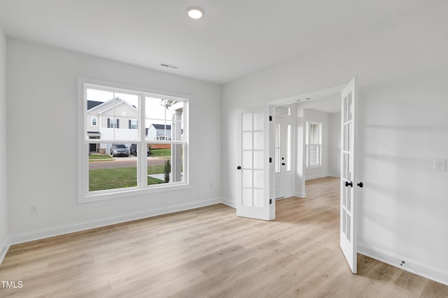 empty room featuring french doors, baseboards, light wood-style flooring, and recessed lighting