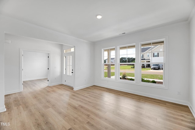 empty room featuring baseboards, light wood-style flooring, and ornamental molding