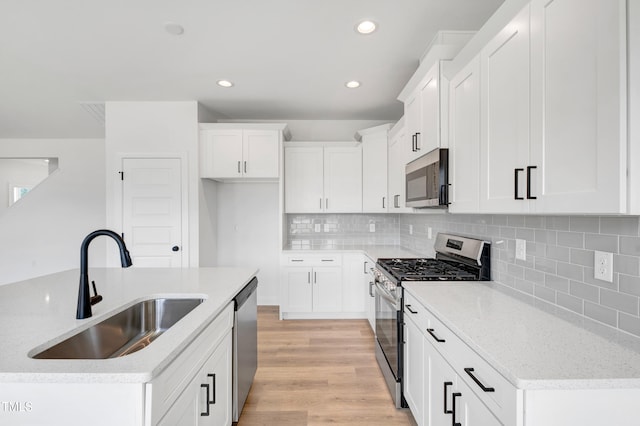 kitchen with stainless steel appliances, a sink, light wood-style floors, recessed lighting, and white cabinets