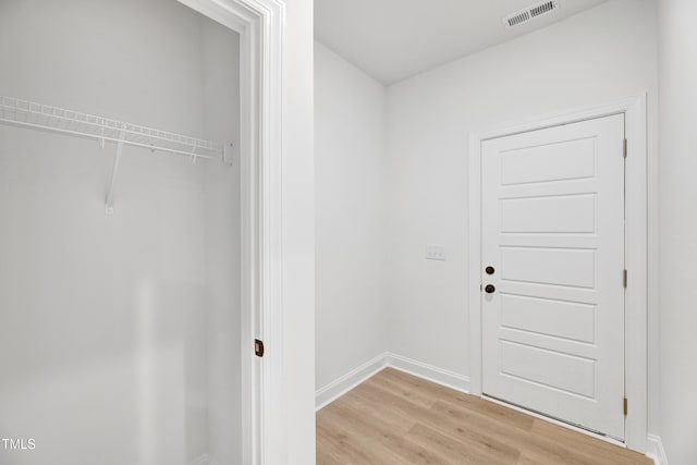 laundry room with light wood-style floors and baseboards