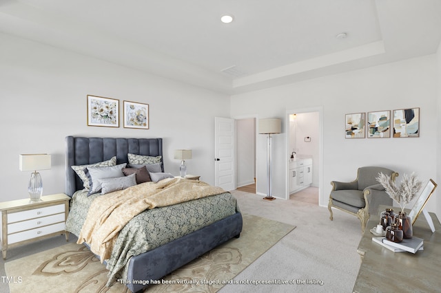 bedroom featuring a tray ceiling, light carpet, connected bathroom, and baseboards