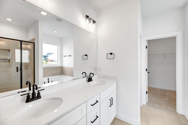 bathroom with a shower stall, tile patterned flooring, a walk in closet, a garden tub, and double vanity