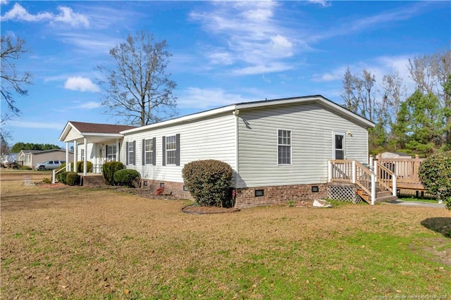 view of side of property with crawl space and a lawn