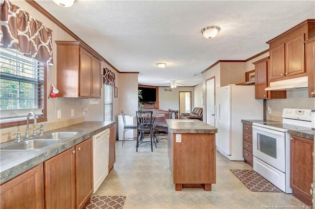 kitchen with white appliances, brown cabinets, a center island, under cabinet range hood, and a sink