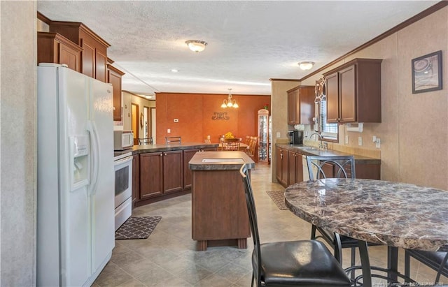 kitchen with white appliances, a sink, hanging light fixtures, a center island, and dark countertops