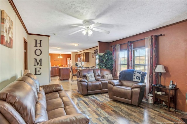 living room featuring ornamental molding, a ceiling fan, a textured ceiling, and wood finished floors