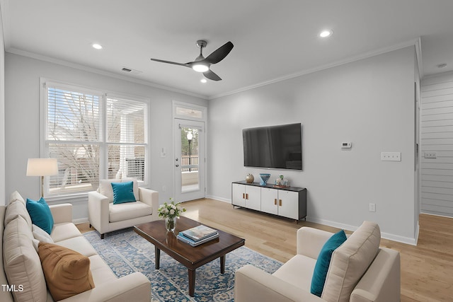 living room with light wood-style floors, baseboards, and crown molding