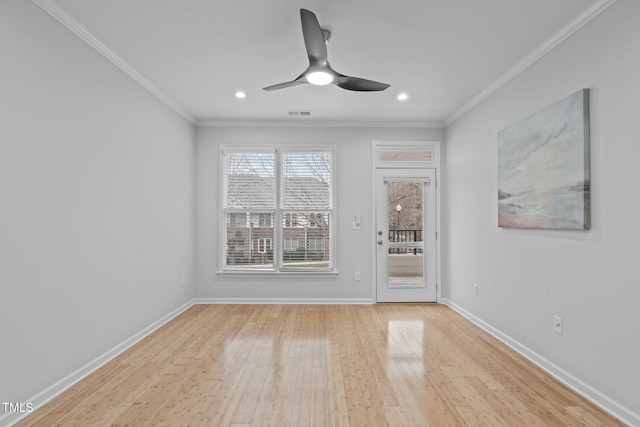 empty room with baseboards, light wood finished floors, and crown molding