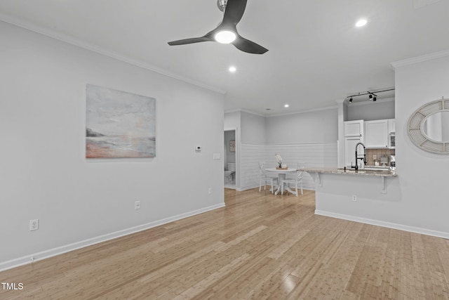 unfurnished living room featuring a ceiling fan, light wood-style flooring, crown molding, a sink, and recessed lighting