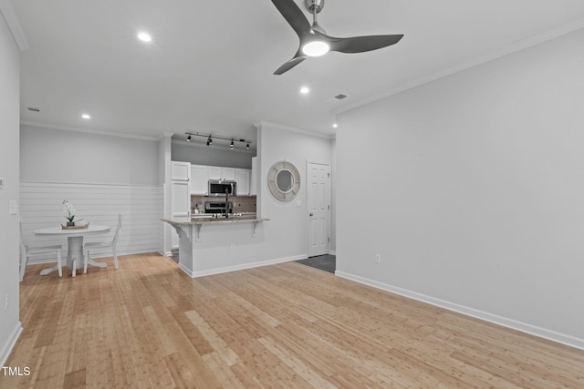 unfurnished living room featuring visible vents, ornamental molding, a ceiling fan, and light wood-style floors