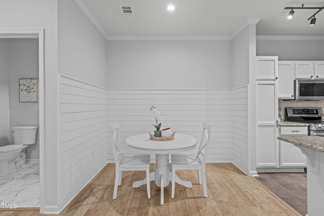 dining space featuring baseboards, visible vents, ornamental molding, and track lighting