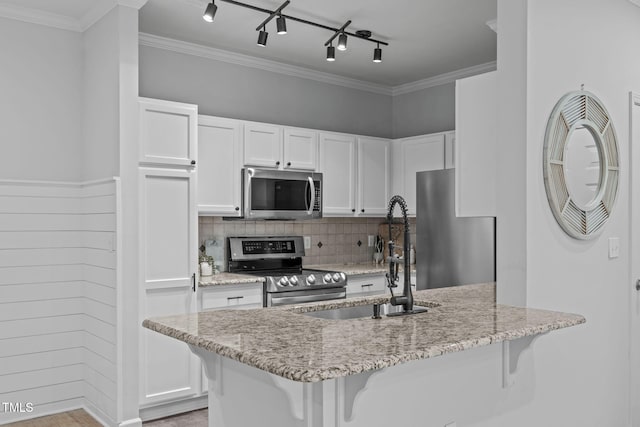 kitchen with a kitchen breakfast bar, appliances with stainless steel finishes, a sink, and white cabinets