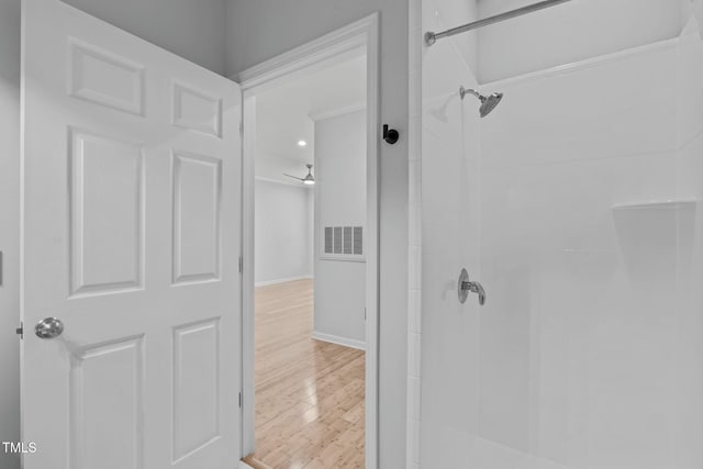 bathroom with baseboards, visible vents, a shower, and wood finished floors