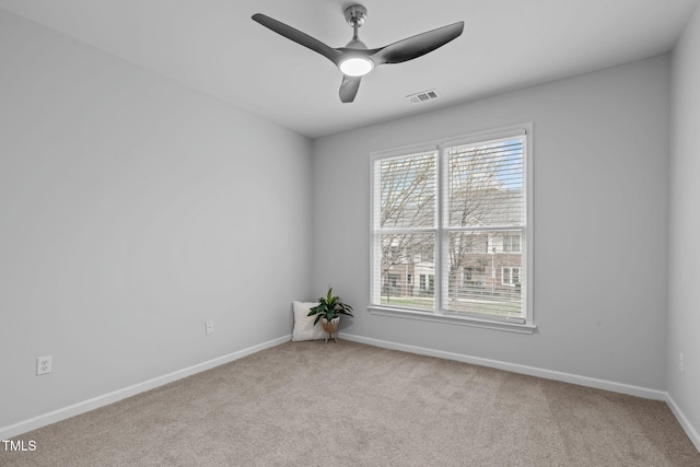 empty room featuring light carpet, a ceiling fan, and a wealth of natural light