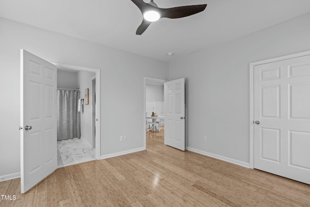 unfurnished bedroom with ensuite bath, light wood-style flooring, and baseboards