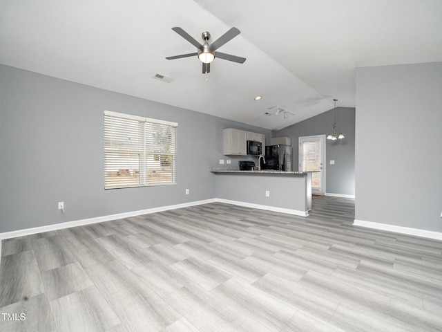 unfurnished living room with light wood-type flooring, ceiling fan with notable chandelier, and vaulted ceiling