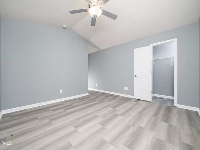 unfurnished bedroom with a walk in closet, a closet, ceiling fan, and lofted ceiling