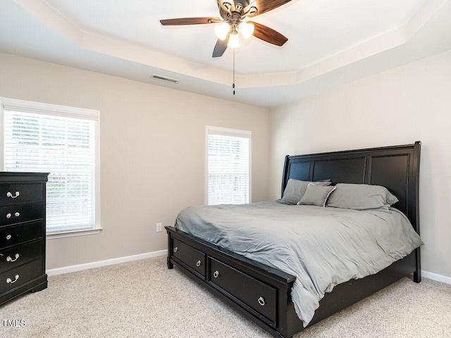 carpeted bedroom featuring ceiling fan and a tray ceiling