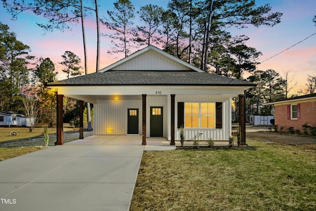 view of front of home with a yard, a porch, and a carport