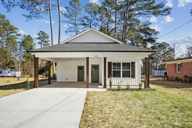 bungalow-style house featuring covered porch, a front yard, and a carport