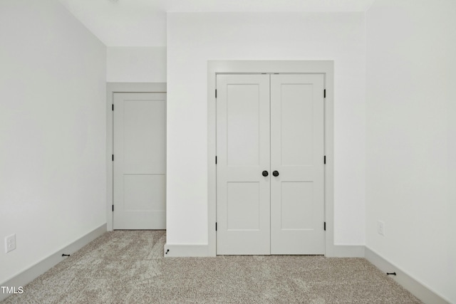 unfurnished bedroom with a closet and light carpet