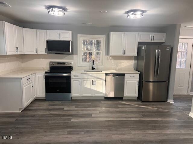 kitchen with dark hardwood / wood-style flooring, white cabinetry, sink, and appliances with stainless steel finishes