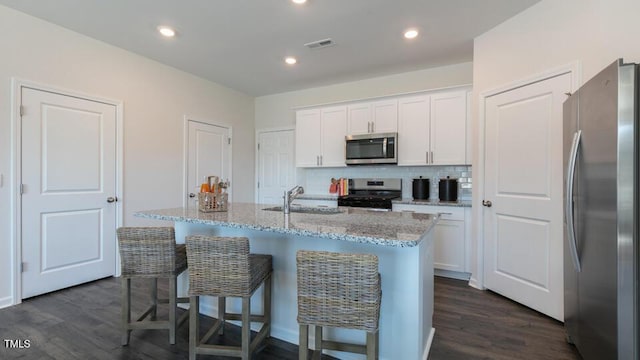 kitchen featuring white cabinets, appliances with stainless steel finishes, light stone countertops, dark wood-style floors, and tasteful backsplash