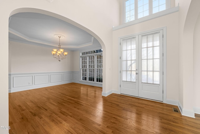 foyer entrance with ornamental molding, french doors, hardwood / wood-style floors, and an inviting chandelier