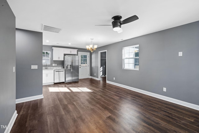 unfurnished living room with ceiling fan with notable chandelier, sink, dark wood-type flooring, and a wealth of natural light