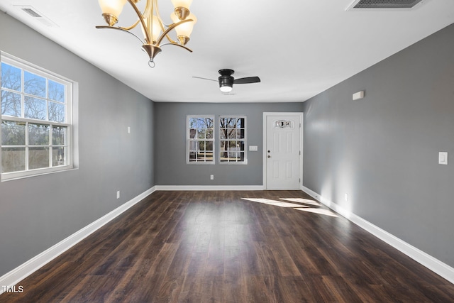 spare room with dark hardwood / wood-style floors and ceiling fan with notable chandelier