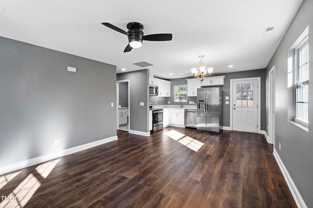 unfurnished living room featuring dark hardwood / wood-style flooring and ceiling fan with notable chandelier