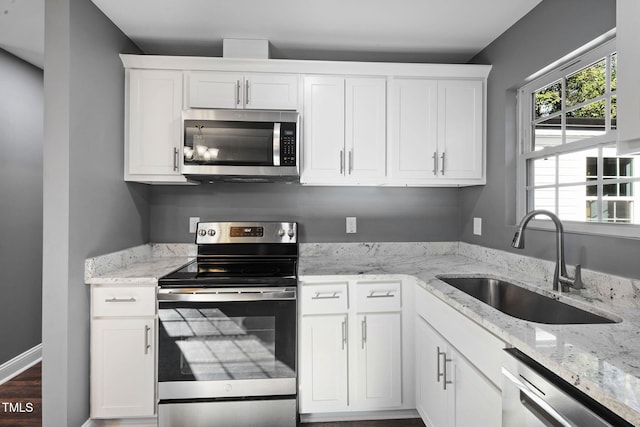 kitchen with light stone countertops, sink, white cabinetry, and stainless steel appliances