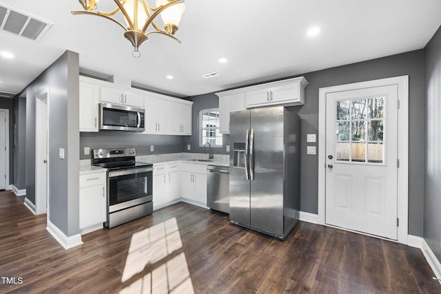 kitchen with hanging light fixtures, white cabinetry, sink, and appliances with stainless steel finishes