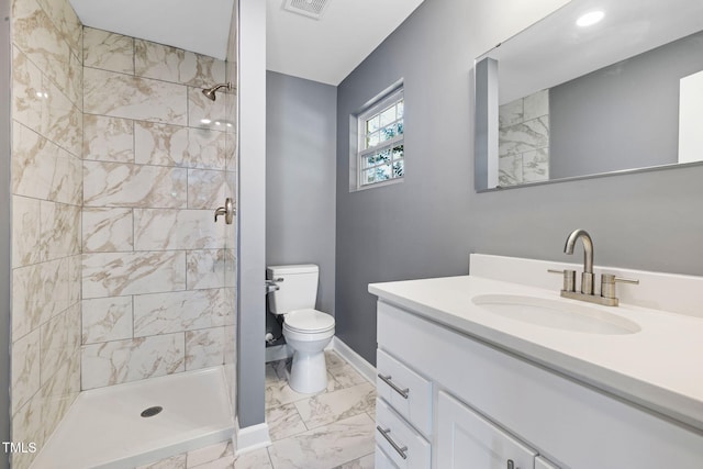 bathroom with vanity, toilet, and tiled shower